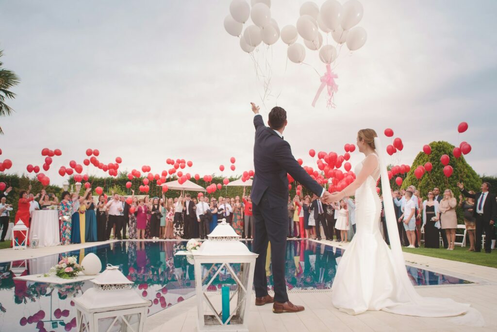 foto de pareja casandose con globos, invitados y un evento muy organizado delante de una pisicna