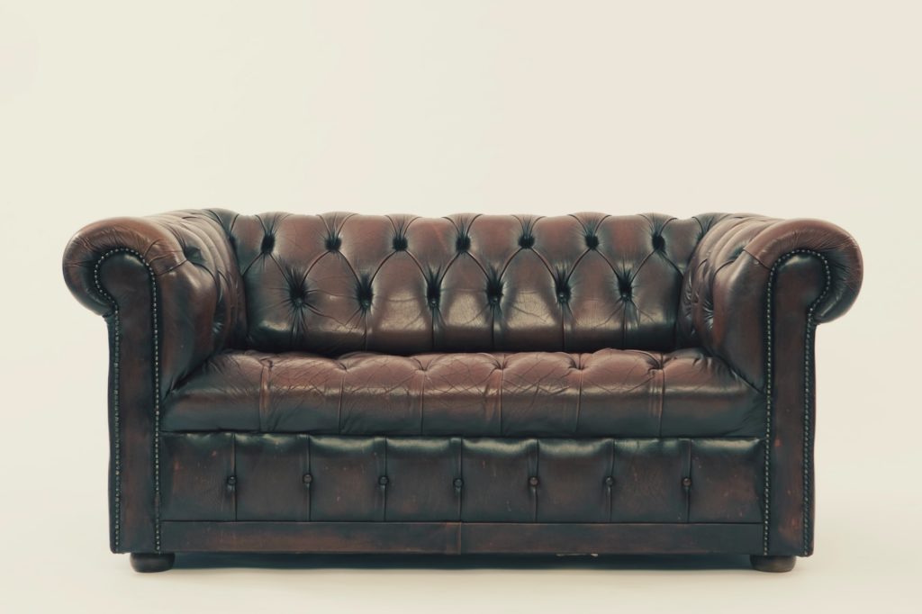 Trabajo de artesano de cueros y piel, sofa chesterfield de cuero marrón.